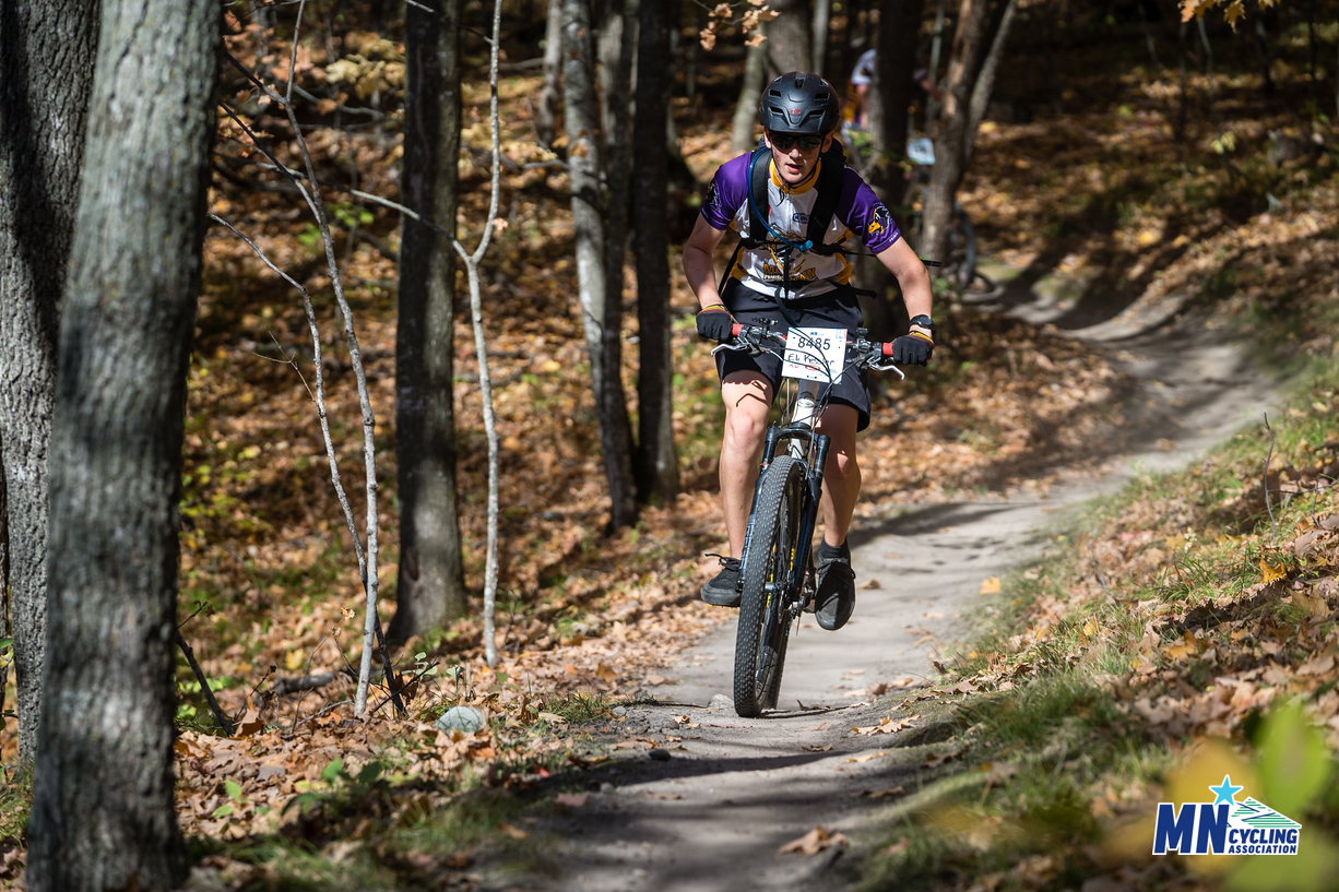 Photo of Eli Kessler mountain biking in the woods in Minnesota.